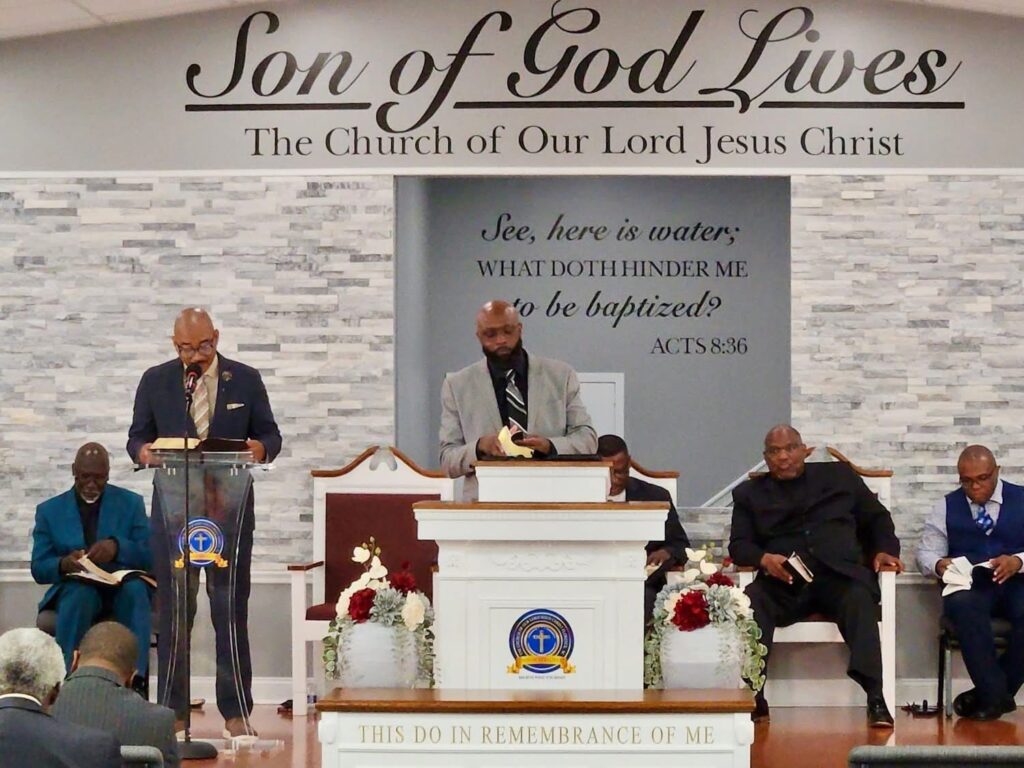 Clergy members lead a worship service at the Son of God Lives church, emphasizing baptism and community, with congregants engaged in prayer and study.